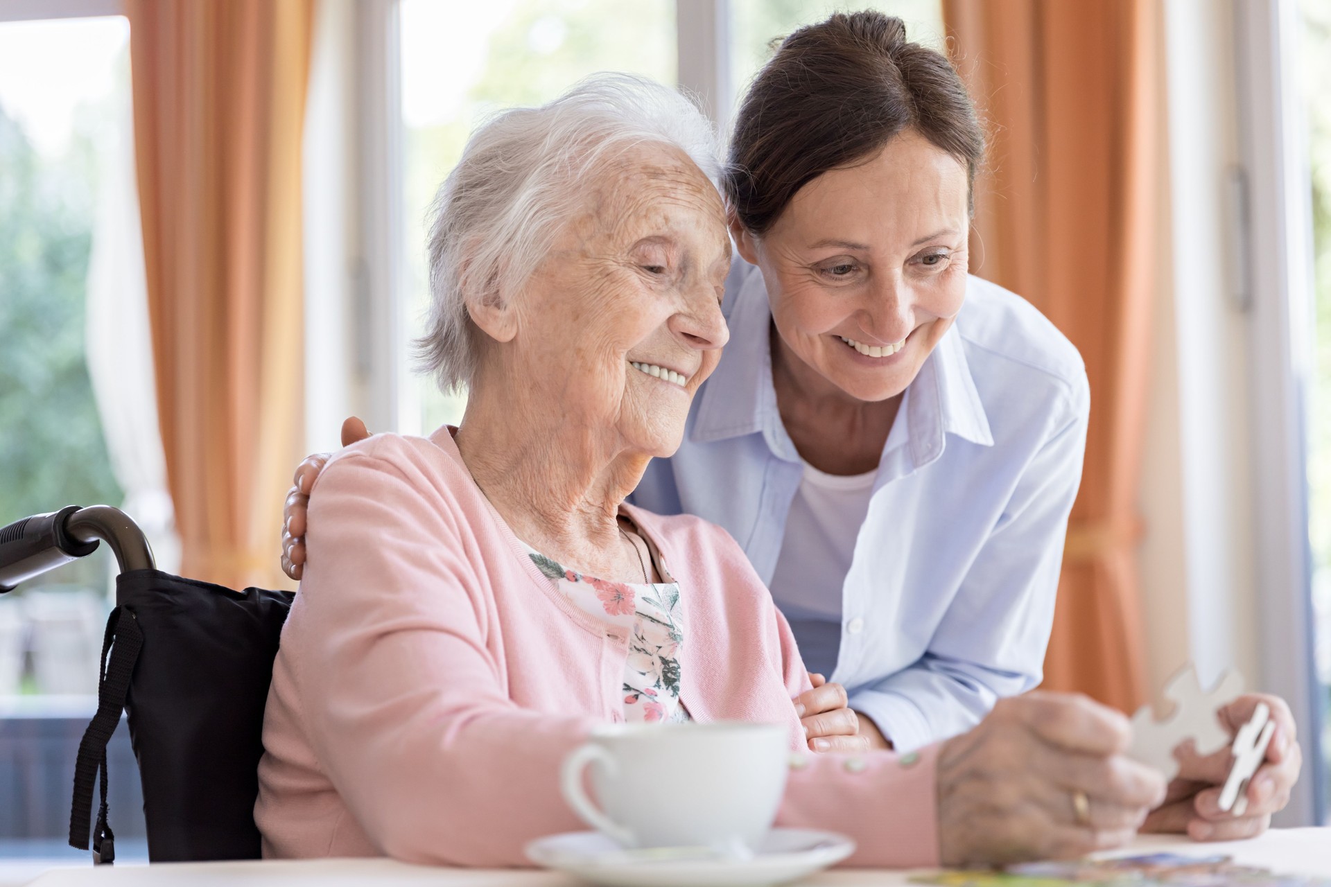 A family works on a puzzle with a senior, highlighting social engagement in a senior care community.